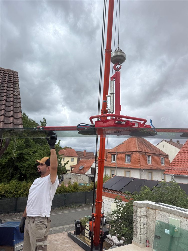Monteur setzt eine Glasscheibe mit Glasheber bei der Fenstermontage ein