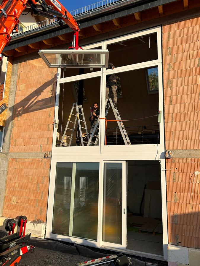 Monteure setzen ein gro&szlig;es Fensterelement mit Glasheber ein